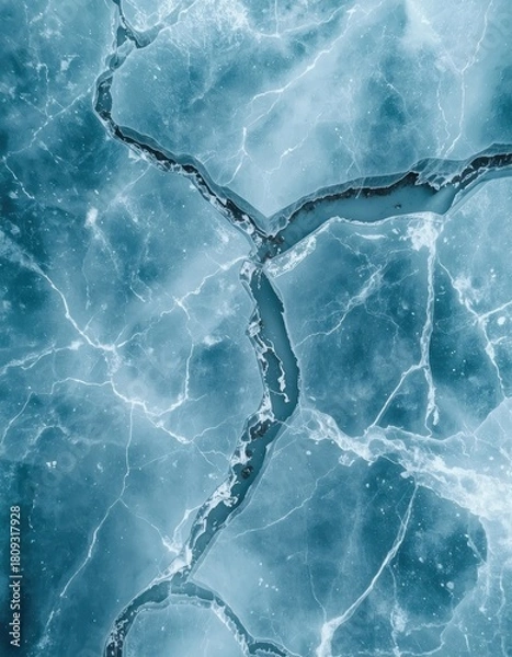 Fototapeta Abstract aerial view of deep cracks and fissures fracturing the surface of a frozen blue lake, creating a natural textured background
