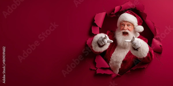 Fototapeta Surprised Santa Claus Pointing Finger Through Torn Red Paper Hole - Christmas Sale and Announcement Concept