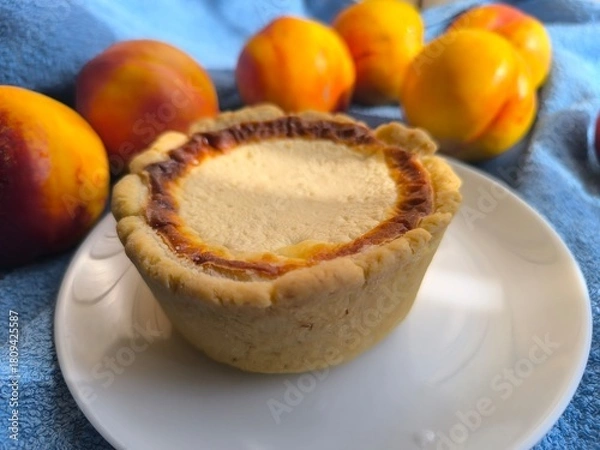 Fototapeta freshly baked bun with sour cream filling on a white plate surrounded by ripe nectarines.