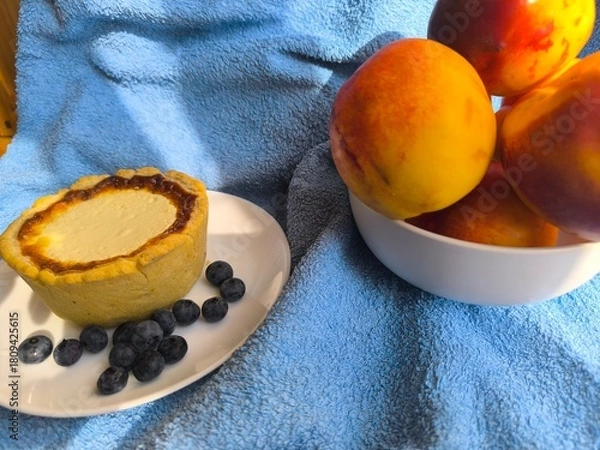 Fototapeta freshly baked bun with sour cream filling on a white plate surrounded by ripe nectarines.