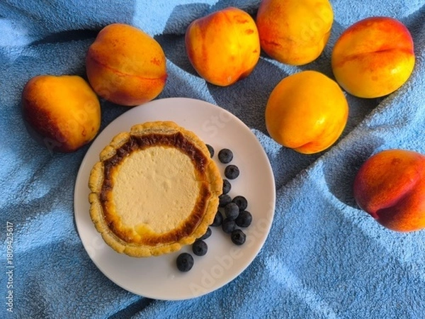 Fototapeta freshly baked bun with sour cream filling on a white plate surrounded by ripe nectarines.