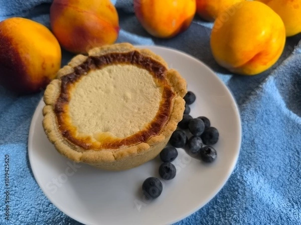 Fototapeta freshly baked bun with sour cream filling on a white plate surrounded by ripe nectarines.