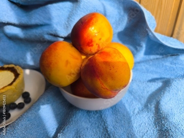 Fototapeta freshly baked bun with sour cream filling on a white plate surrounded by ripe nectarines.