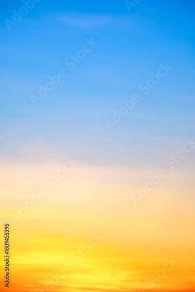 Obraz Sunset or sunrise sky with a vibrant gradient of orange, gold, and soft blue. Clear atmosphere with wispy clouds. Peaceful, natural light background. hope, freedom, new day Concepts, Vertical