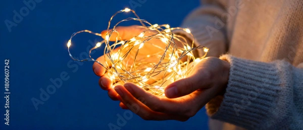 Obraz Person holding string lights creating a warm, cozy atmosphere for holiday decorations or festive celebrations during winter season