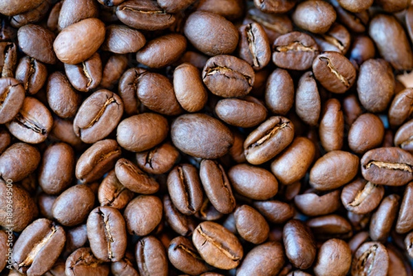 Fototapeta Rich roasted coffee beans fill the frame in a tactile macro; warm tones, oily sheen and shallow depth create a gourmet background for branding, packaging and natural coffee lifestyle