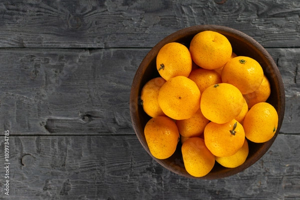 Fototapeta Fresh Citrus Medley: Top View of Vibrant Mandarin Oranges in Wooden Bowl on Rustic Surface