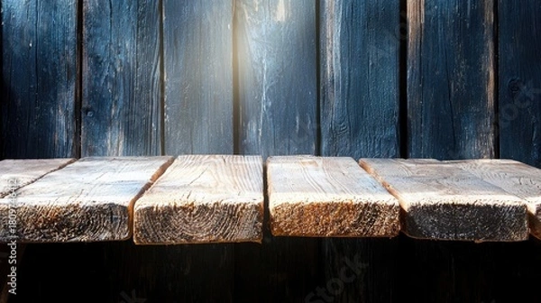 Fototapeta A rustic, weathered wooden shelf sits in front of a dark blue wooden plank wall, with shafts of light illuminating the scene.