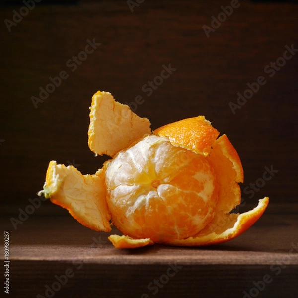 Obraz Peeled mandarin on a wooden dark background. Fruit of tangerine without skin. Soft side light on the dark. Healthy eating concept, vegetarian, vegetable healthy food.