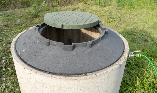 Obraz Concrete well ring with water hose.