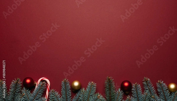 Obraz Christmas fir border with red gold baubles and candy cane on red background