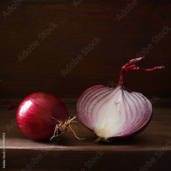 Obraz Still life with red onion on a dark background. Red onion in a cut on a wooden board in a low key. Beautiful side soft light. Vegetables, the concept of healthy eating. 