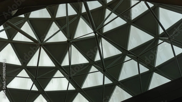 Fototapeta Close-up view of a geometric glass dome with triangular panels and steel framework creating a modern architectural pattern.