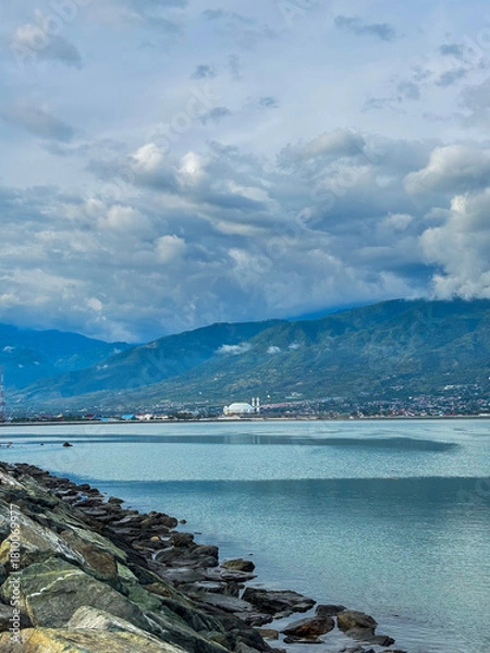 Fototapeta Serene coastal view in palu city featuring calming blue waters and majestic mountains in the distance perfect for travel campaigns