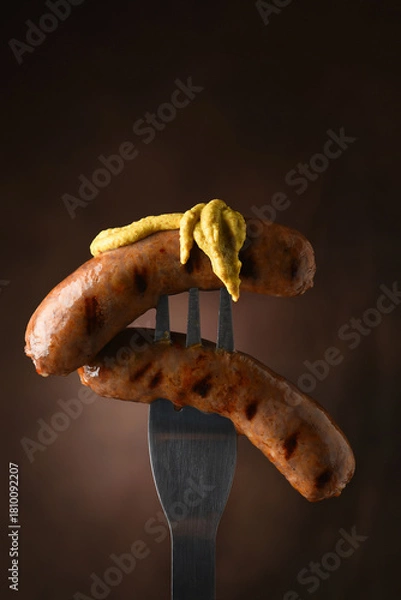 Fototapeta Grilled sausages on fork with mustard