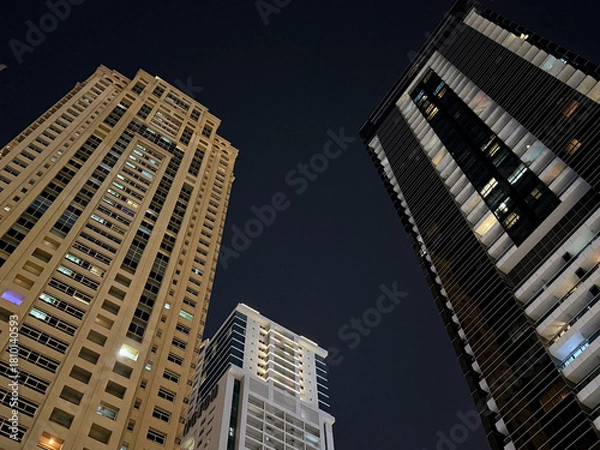 Fototapeta Modern high-rise buildings against dark night sky. Urban architecture and city lifestyle concept, view from below.