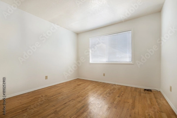 Fototapeta An empty bedroom featuring hardwood floors and a wellplaced window