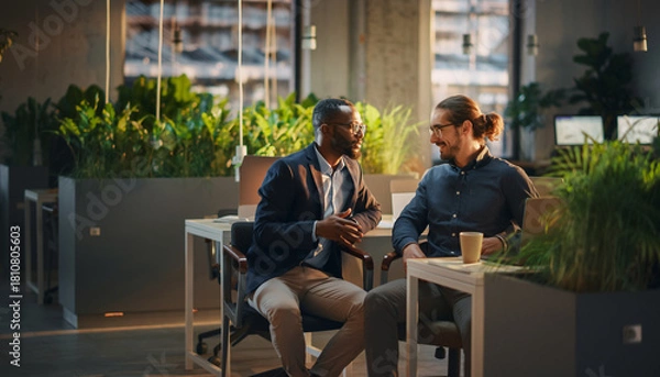 Obraz Business conversation between coworkers in relaxed and positive mood, modern office with greenery, natural light, casual attire, teamwork, friendly atmosphere, collaboration
