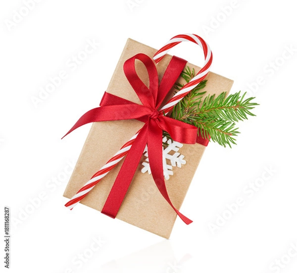 Obraz Christmas gift box wrapped in craft paper decorated with candy red cane in white stripes and fir branches with snow isolated on white background with clipping path. Design element