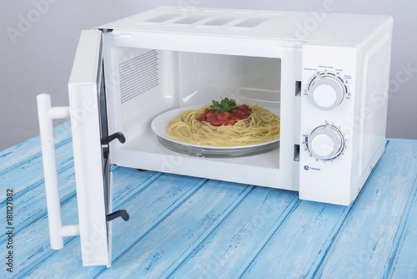 Obraz A new white microwave oven, on a blue wooden surface for heating food
