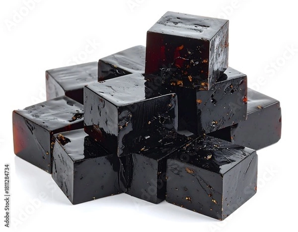 Fototapeta Cubes of dark, translucent jelly with small inclusions are piled on a white background.