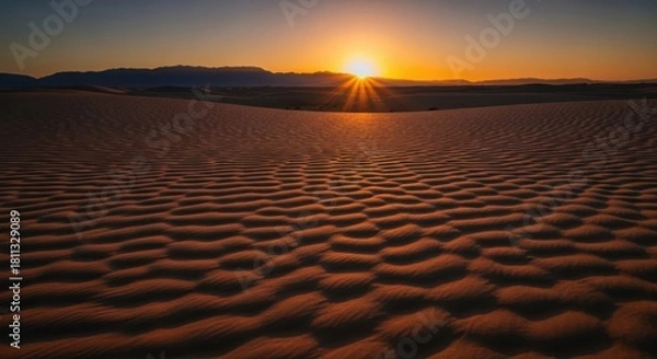 Obraz Golden sunset illuminates rippled sand dunes in a vast desert landscape with distant mountains