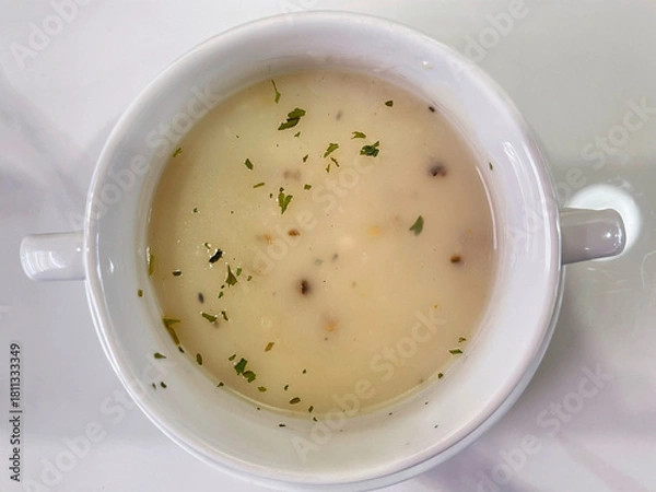 Obraz Creamy mushroom soup served in a white bowl, garnished with herbs.
