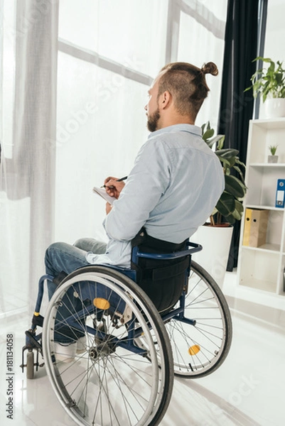 Fototapeta man on wheelchair writing in notebook