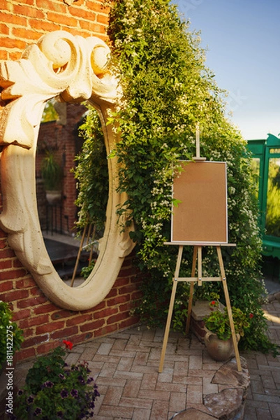 Fototapeta Artistic corner with a mirror and blank easel in a garden
