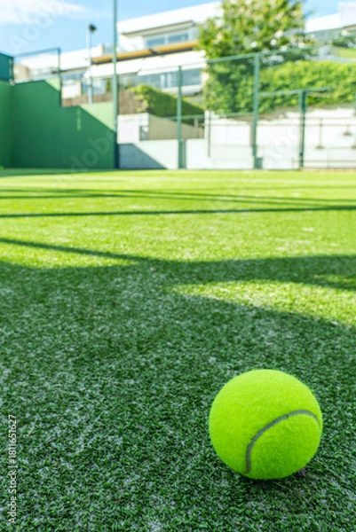 Fototapeta A tennis and padel court with a green artificial grass surface with a tennis ball in the corner