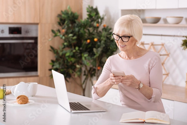 Obraz Nice smiling elderly woman using her smartphone