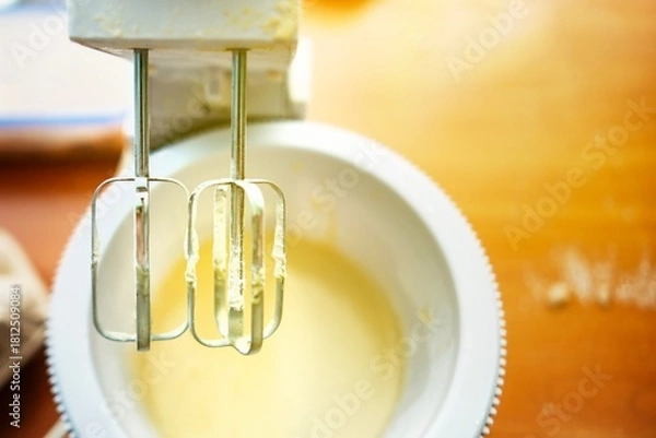 Fototapeta Mixer whisks raised over bowl with dough traces after finishing baking preparation