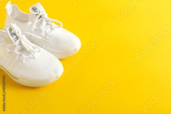 Obraz White summer sneakers stand on a yellow background.	