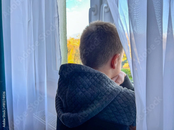 Fototapeta Boy looking out window, thinking, feeling solitude