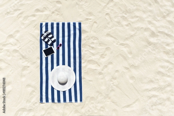 Fototapeta Widok z góry na piaszczystą plażę z ramą na ręczniki i letnimi akcesoriami. Tło z miejsca na kopię i widoczną teksturą piasku.