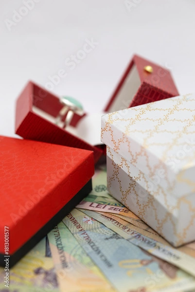 Fototapeta small red and white gift boxes with jewelry and scattered money on a white background, symbolizing expensive gifts, luxury, spending, and financial exchange