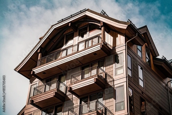 Fototapeta Traditional wooden chalet with multiple balconies under a partly cloudy sky showcasing rustic alpine architecture