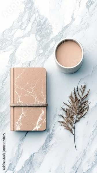 Obraz A minimalist composition featuring a marble-patterned notebook, a cup of coffee, and a dried plant stem arranged on a marble surface.