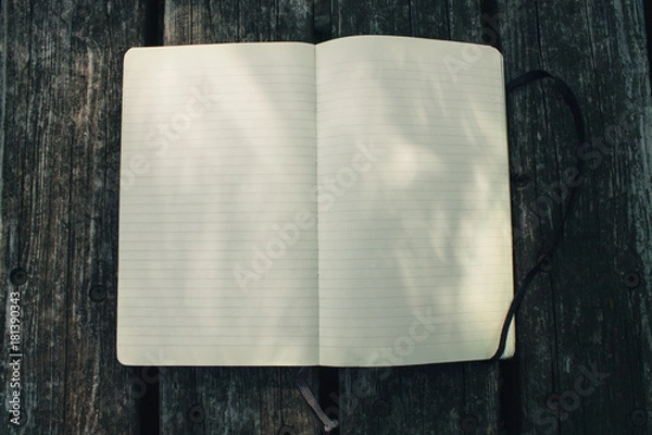 Fototapeta Blank empty moleskine notepad see from top on wooden table in a park