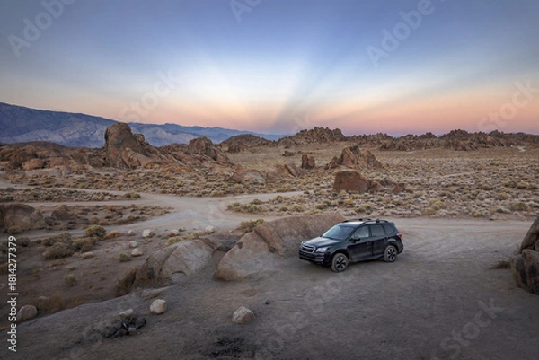 Fototapeta Rocks and a Camper Car Illuminated by Sunset Light