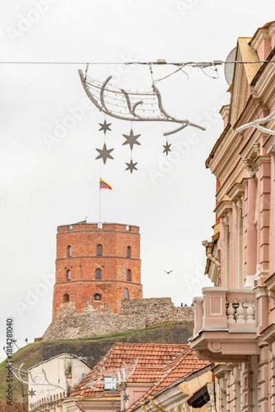 Fototapeta A cozy, festive street in Vilnius Old Town with Gediminas tower and Christmas decorations and ornaments creating a charming holiday atmosphere
