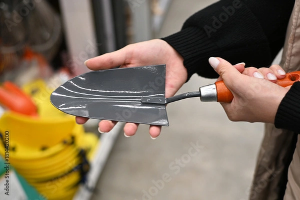 Fototapeta Person holds a gardening tool in a store while shopping for supplies in fall