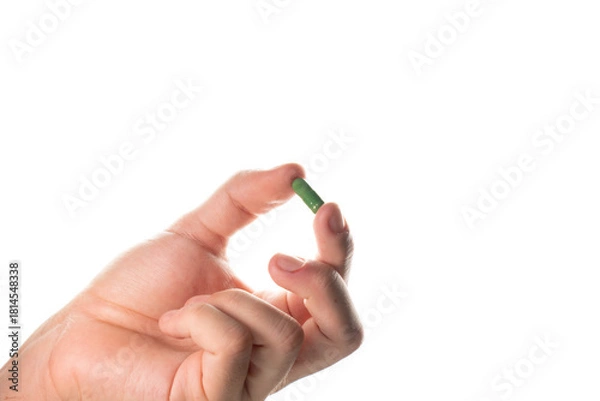 Obraz Detailed close-up of a male hand pinching a green capsule. Focus on the texture and color, suitable for pharmaceutical and medical articles.