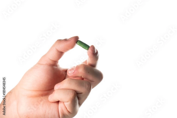 Fototapeta Detailed close-up of a male hand pinching a green capsule. Focus on the texture and color, suitable for pharmaceutical and medical articles.