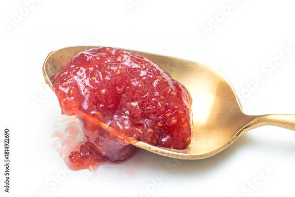 Fototapeta chunky red raspberry jam resting on a vintage gold-toned spoon. The preserves show seeds and texture, isolated on a clean white background. Perfect for food, breakfast, and sweet concepts.