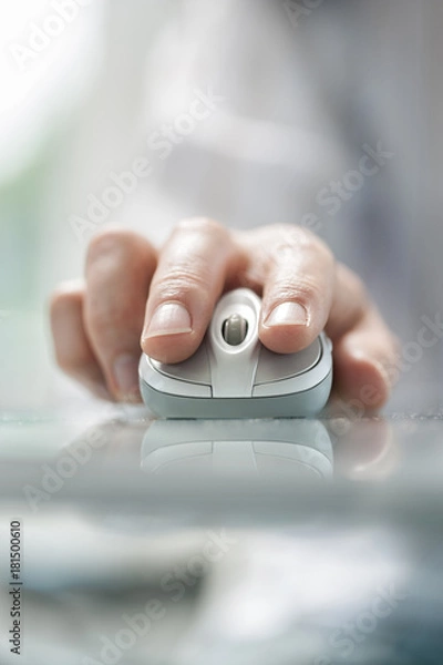 Obraz Man's hand using cordless mouse on glass table.