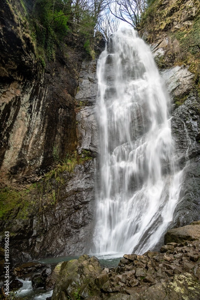 Obraz Tall Mirveti Waterfall near Gvara, Georgia, cascading over rocky cliffs surrounded by lush forest. A scenic natural attraction in the Caucasus Mountains.