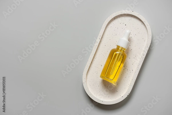 Fototapeta Cosmetic serum in a dropper bottle flat lay on a ceramic tray on a gray background, top view, copy space.