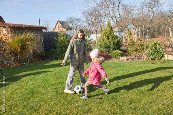 Obraz Sisters playing soccer in autumn garden