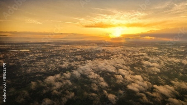 Fototapeta A high-altitude aerial photograph capturing a sunrise above a vast forest with golden morning mist drifting through the treetops